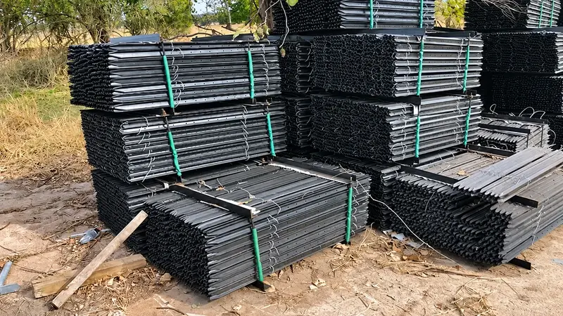 Bundled metal fence posts stacked in a storage yard