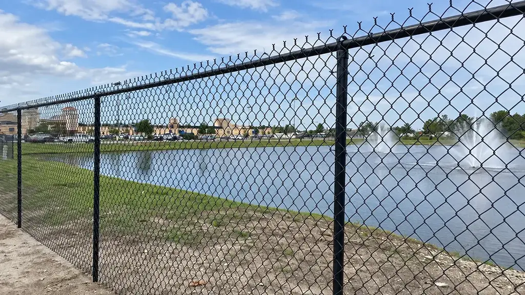 Chain link fence with a top rail beside a waterway