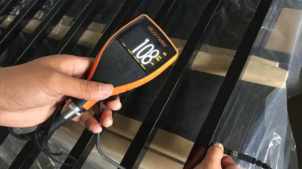 Handheld coating gauge checking a dark gate frame