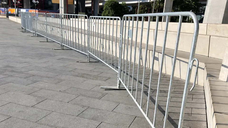 Linked metal crowd barriers along a paved pedestrian route