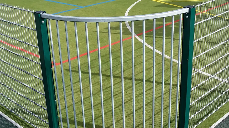 Curved metal rail transition at a sports enclosure corner