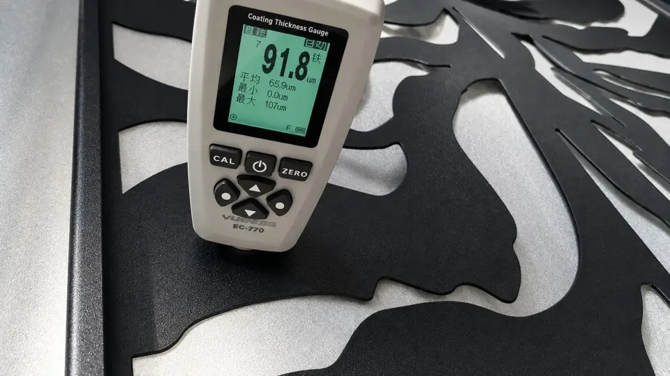 Coating gauge checking a decorative cut metal panel