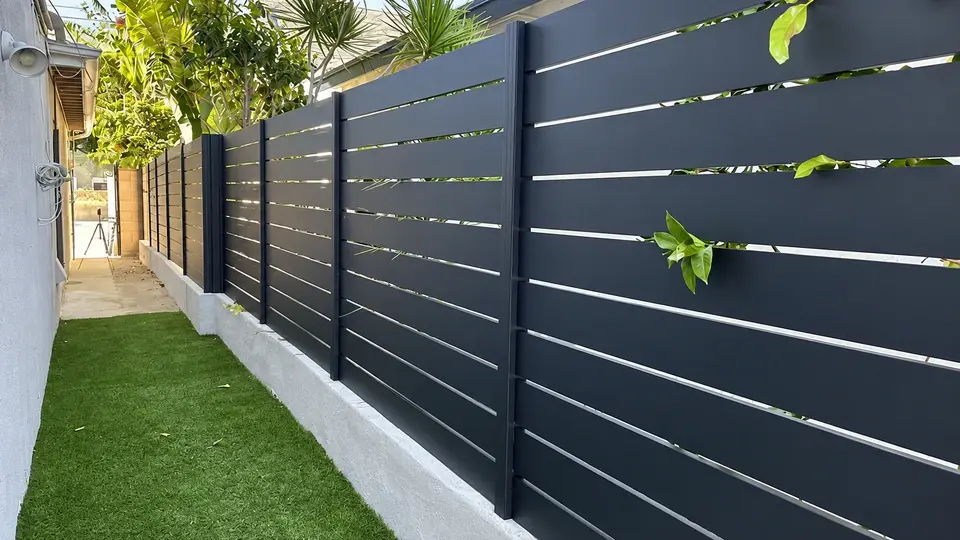 Dark horizontal privacy slats along a garden boundary