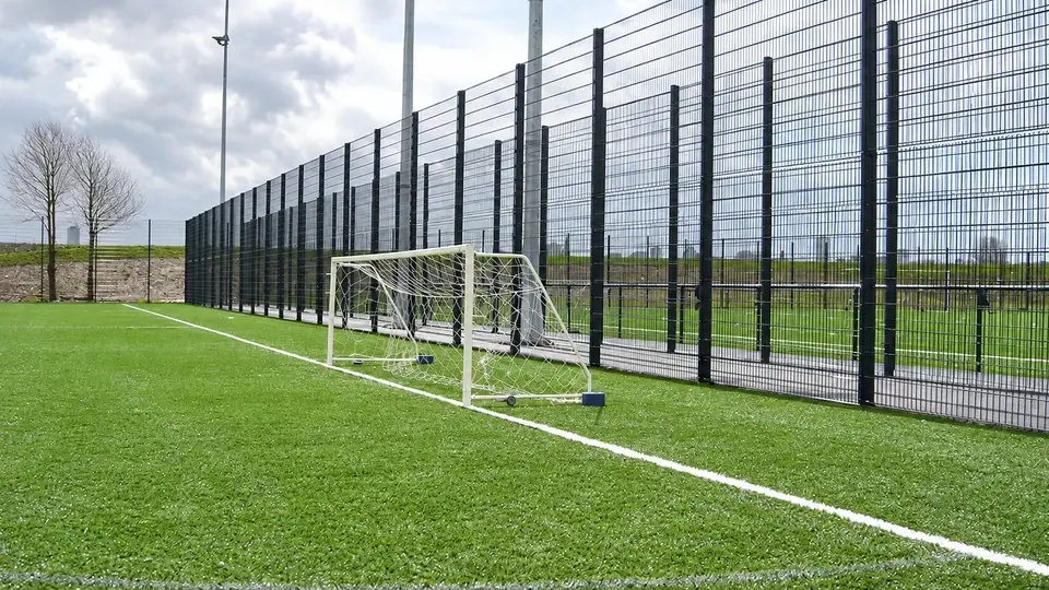 Football pitch with mesh fencing and a goal at the boundary