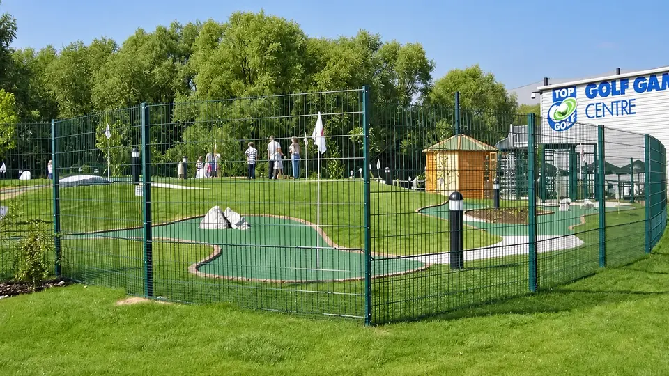 Green mesh fencing around a small golf practice area