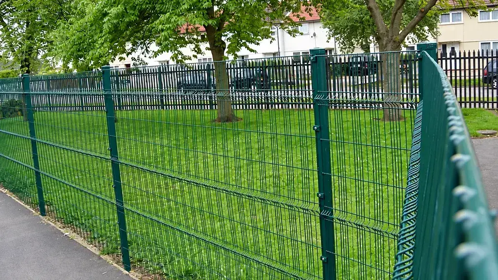 Green welded mesh panels and posts along a garden boundary