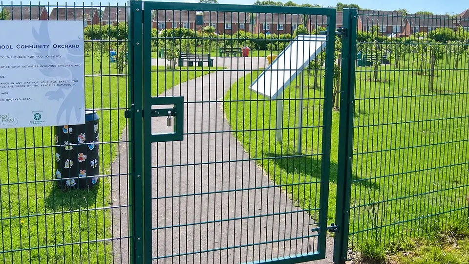Green mesh access gate beside a sports field