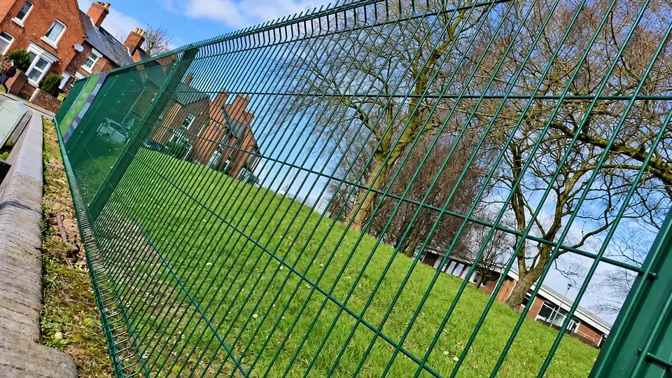 Green welded mesh fencing around a grassed site