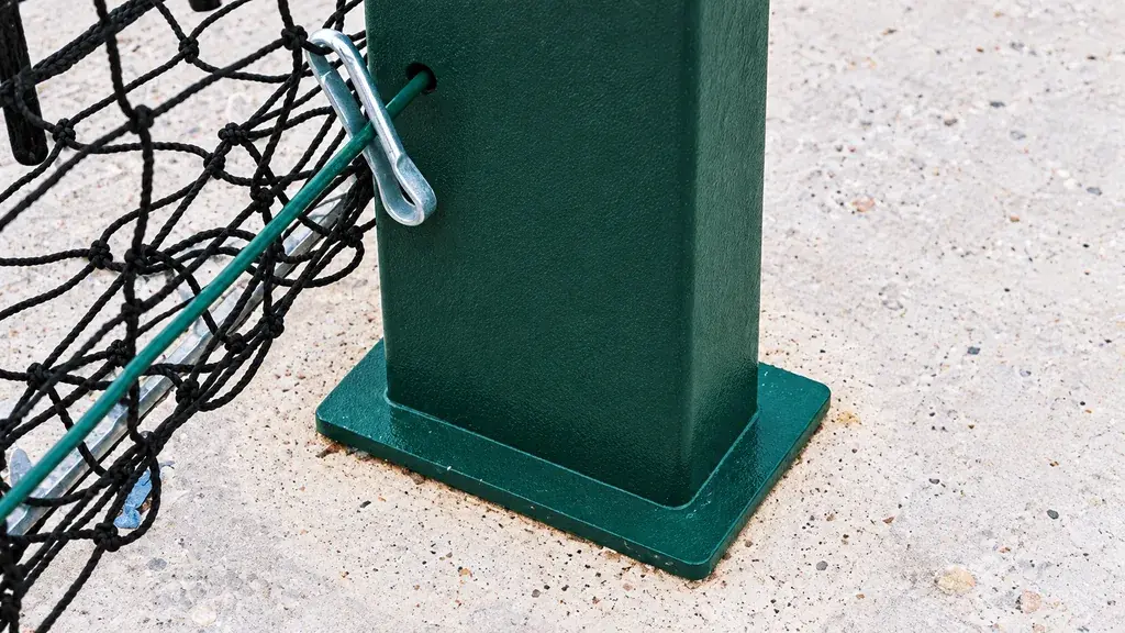 Green fence post base plate on a concrete surface