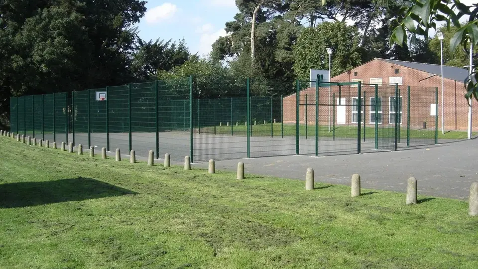 Green mesh sports enclosure beside a grassed public area