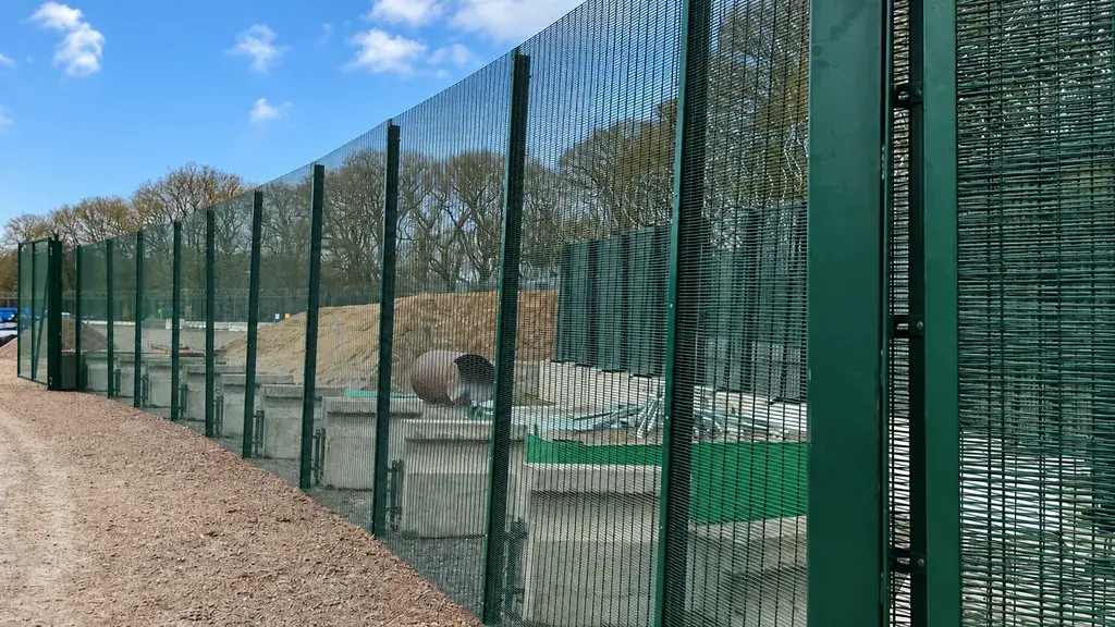 Tall green security mesh panels along a site boundary
