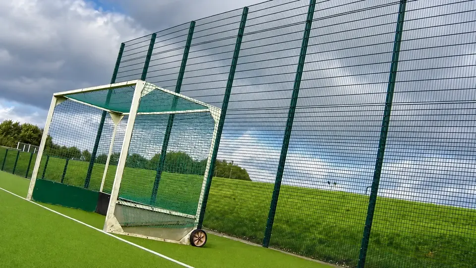 Tall ball retention fencing beside a hockey pitch goal