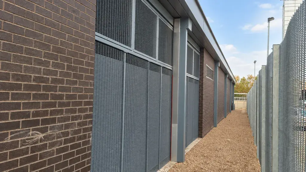 Mesh security fencing beside a brick service building