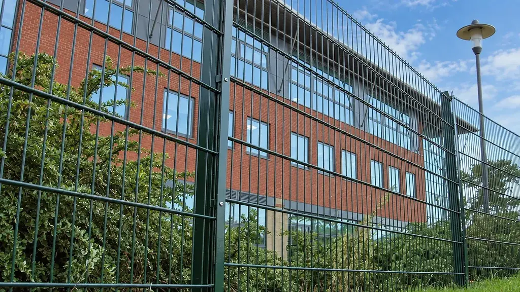 Welded mesh perimeter beside a large brick building