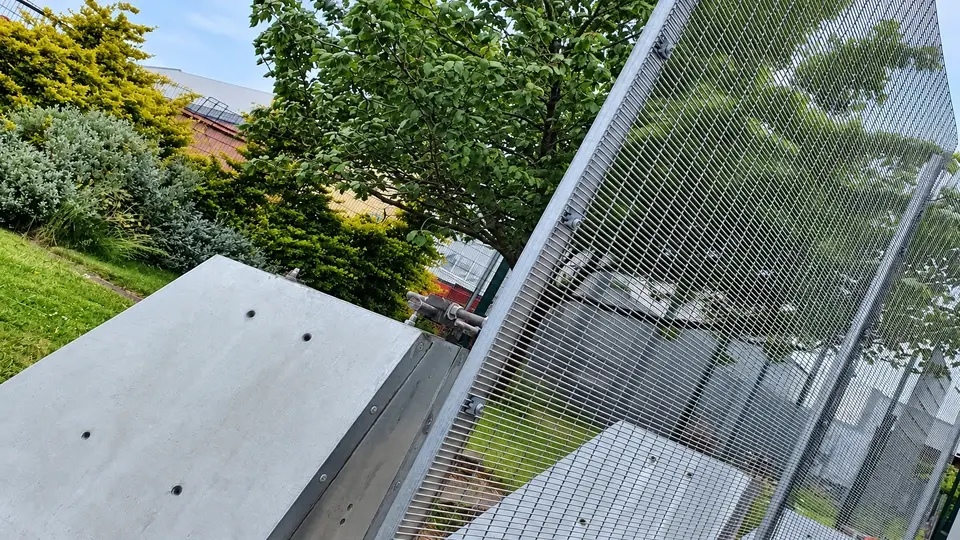 Mesh fence panel beside large concrete support blocks