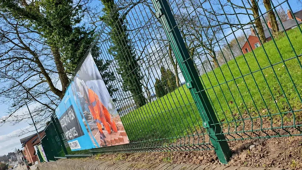 Mesh perimeter fence viewed from a low roadside angle