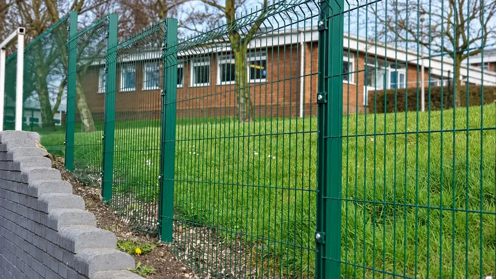 Green welded mesh perimeter mounted above a low wall