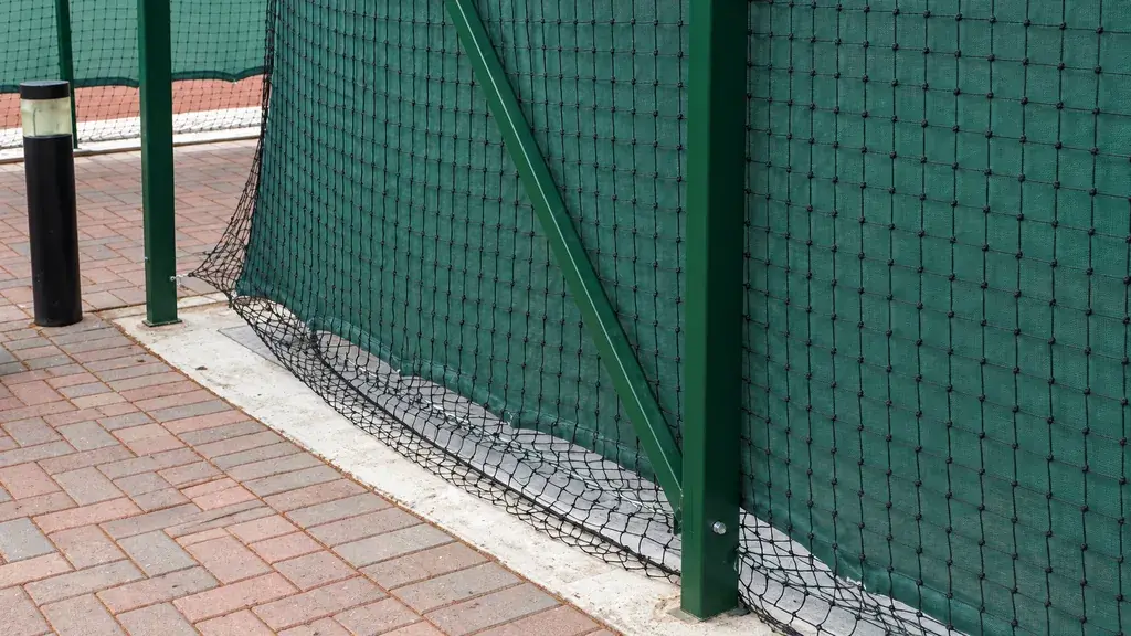 Mesh fencing and posts installed along a paved court edge