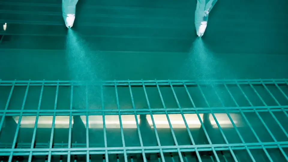 Powder coating guns above a wire mesh panel