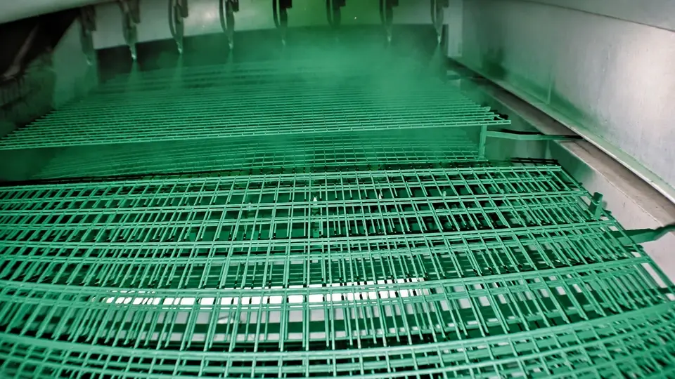 Mesh panels moving through a green powder coating booth
