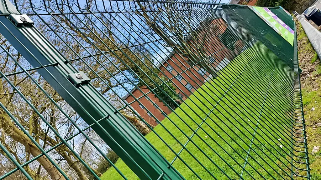 Mesh fence post and panel connections beside a paved path
