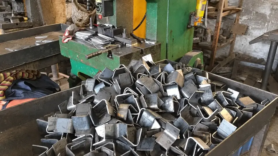Pressed metal brackets beside a forming machine