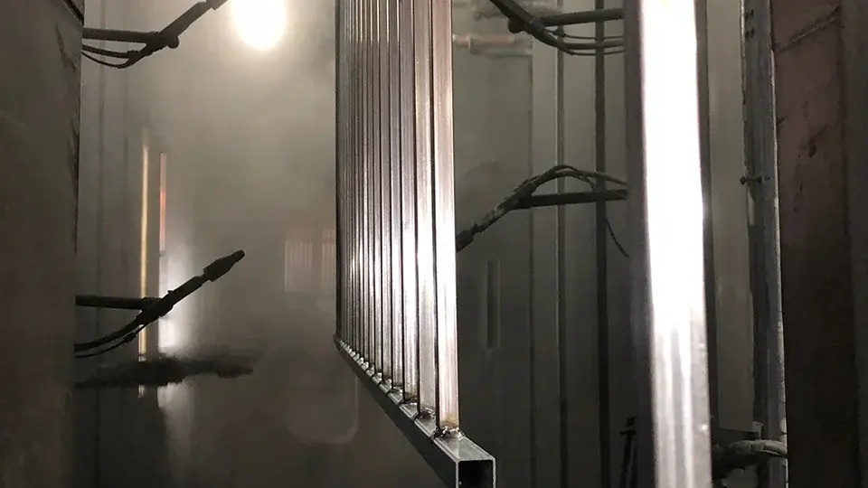 Metal sections hanging inside a powder coating booth
