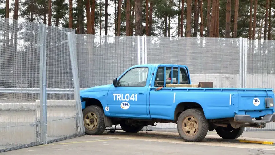 Vehicle impact test setup beside a reinforced perimeter fence