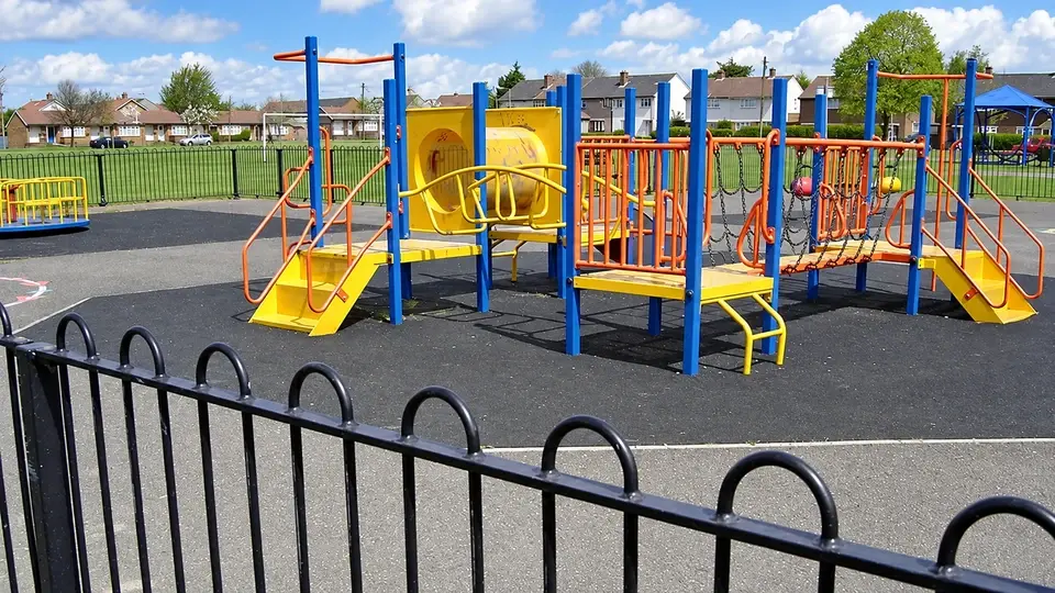 Bow top railings around a playground with climbing equipment