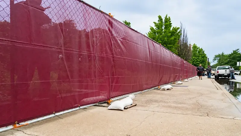 Red screening covering a temporary fence beside a paved route