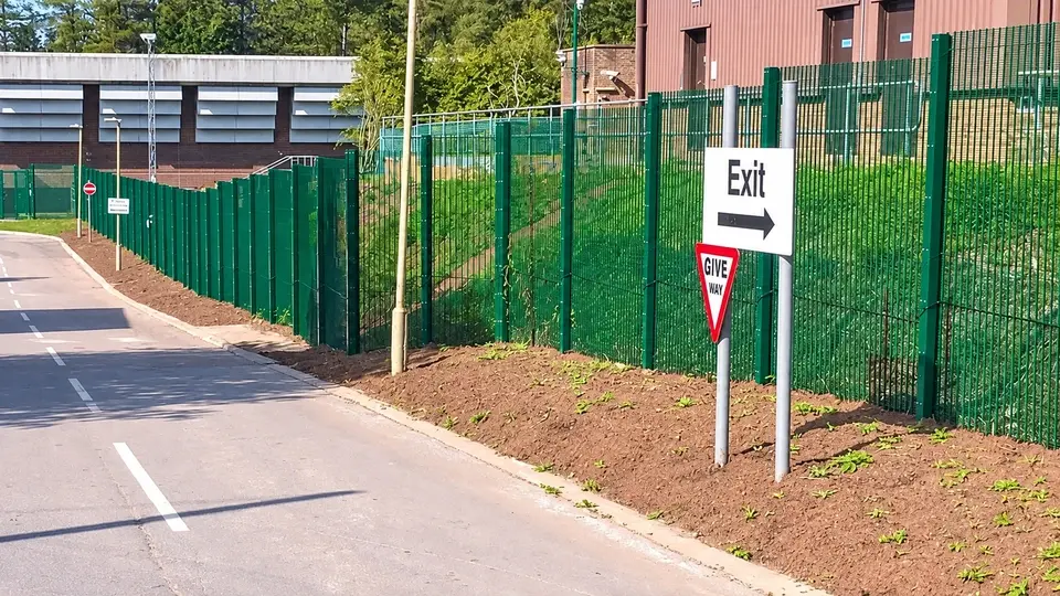 Security fence and pedestrian access beside an industrial building