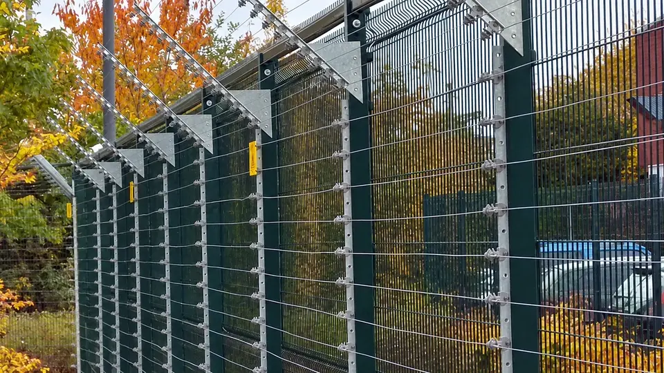 Wire security extensions above a rigid mesh fence