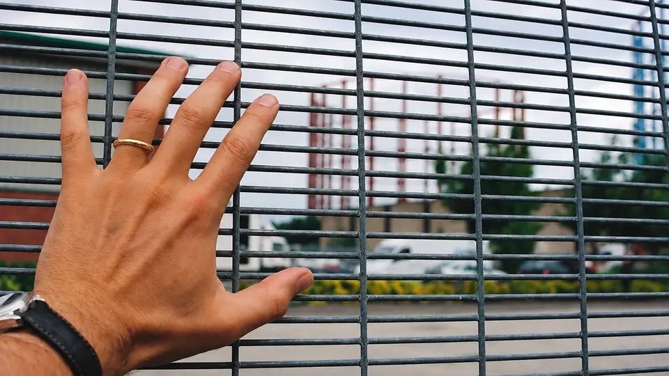 Hand beside closely spaced horizontal security mesh wires