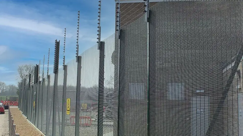 Tall mesh security fence with additional wire topping