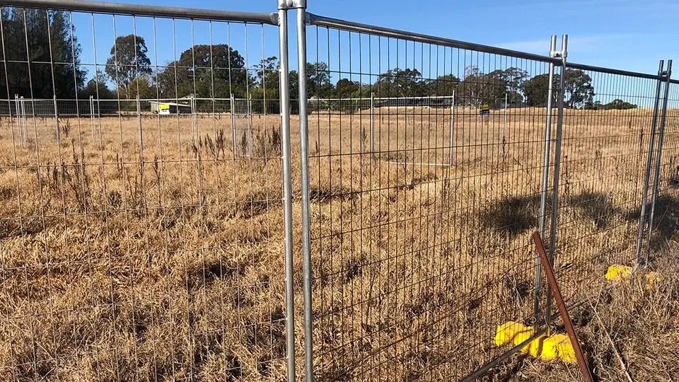 Braced temporary mesh fencing on weighted feet beside a field