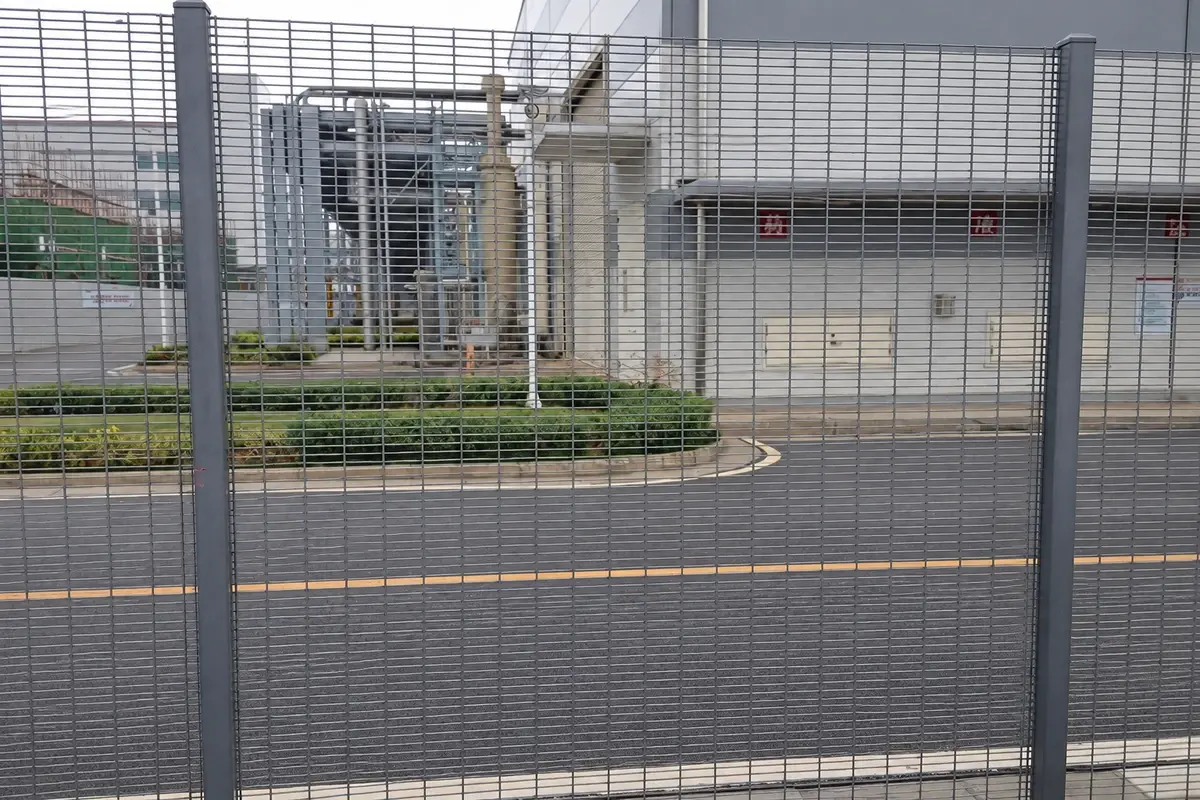 Grey close-spaced mesh panels installed beside an industrial access road