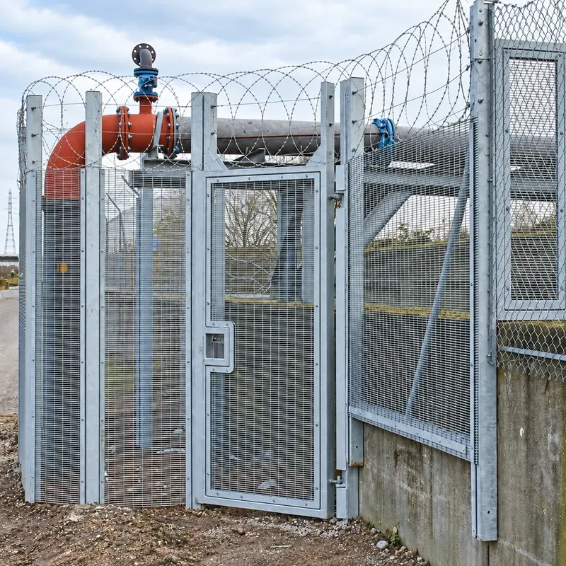 Grey close-mesh pedestrian gate in a steel fence line