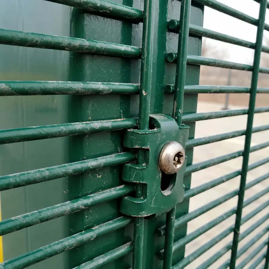 Green mesh wires held against a post by a clip and bolt