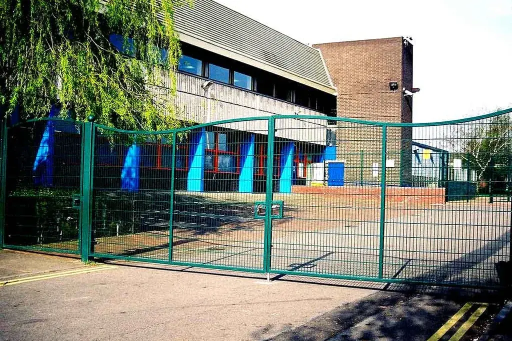 Green double-leaf vehicle gate showing the opening between posts