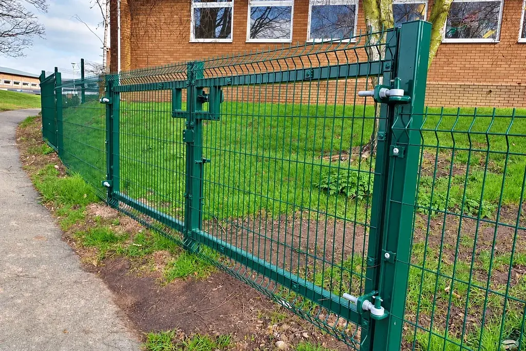 Green folded mesh fence and gate beside a changing ground line