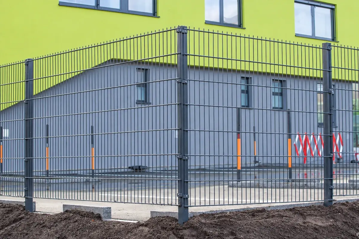Grey twin-wire fence panels with posts around a commercial building