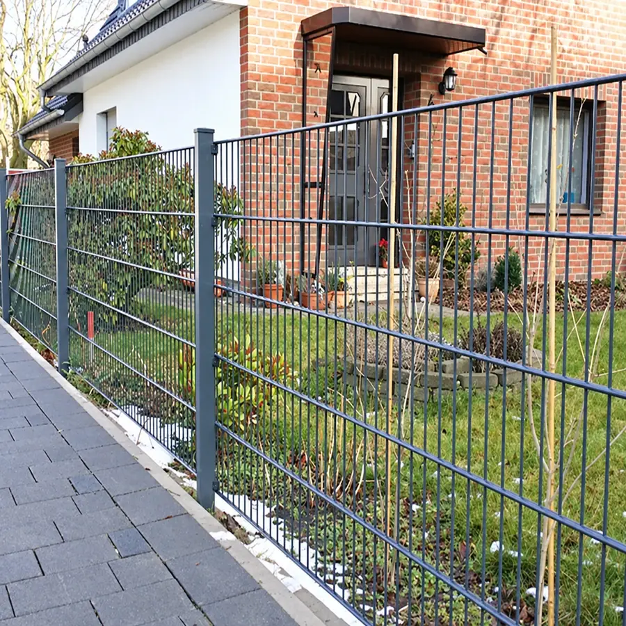 Dark double-wire fence beside a residential garden