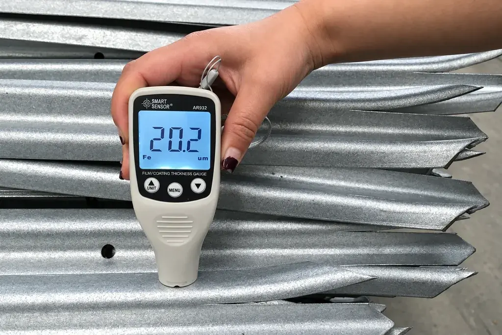 A handheld coating-thickness gauge placed on a galvanised steel pale