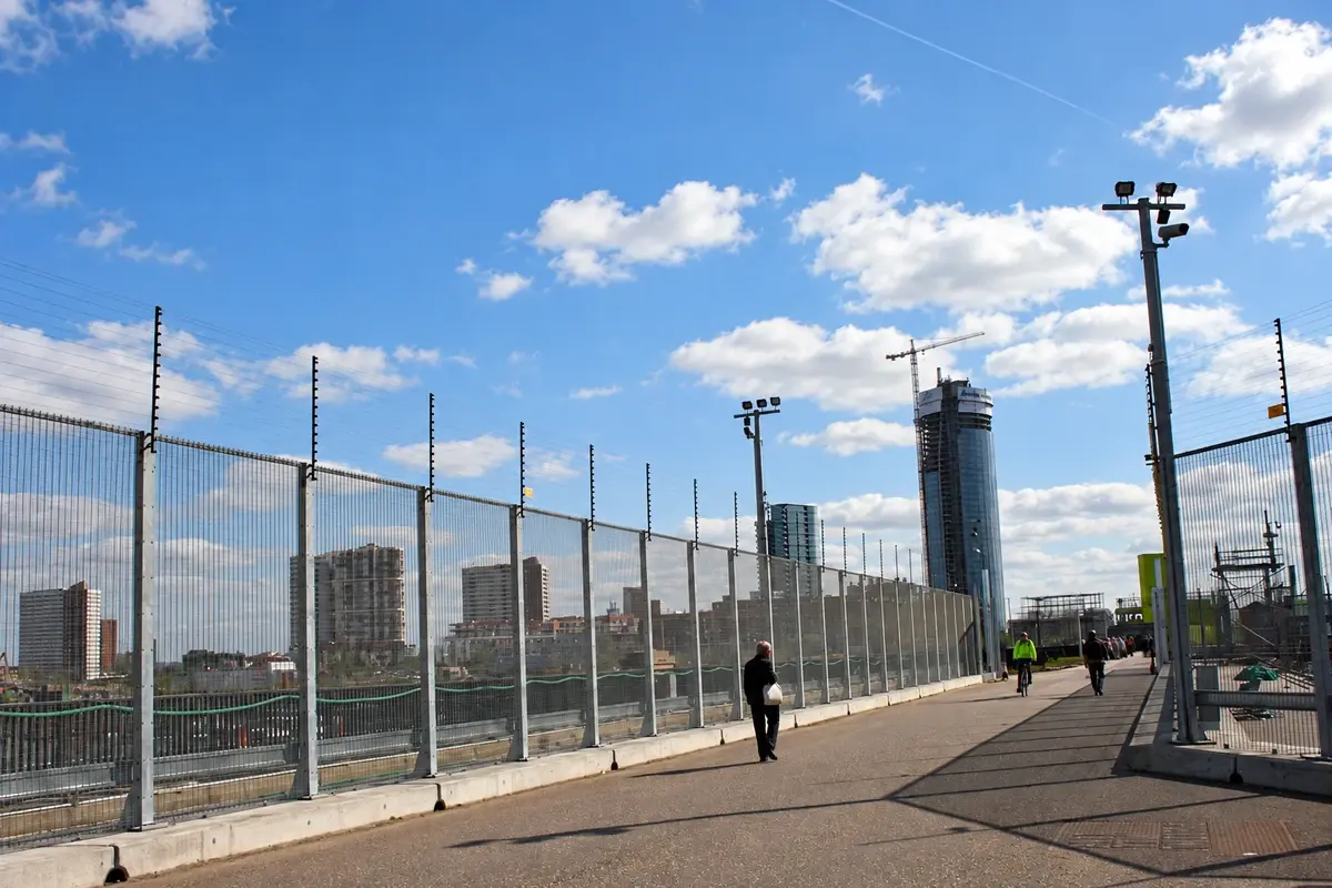 Long run of metal perimeter fencing with regularly spaced posts.