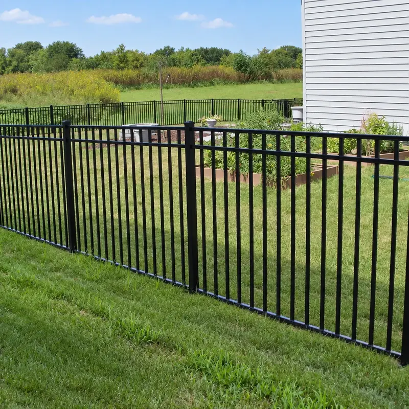 Black flat-top aluminium picket fence along an open grass boundary