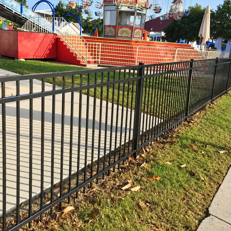 Black aluminium picket fence along a paved public boundary