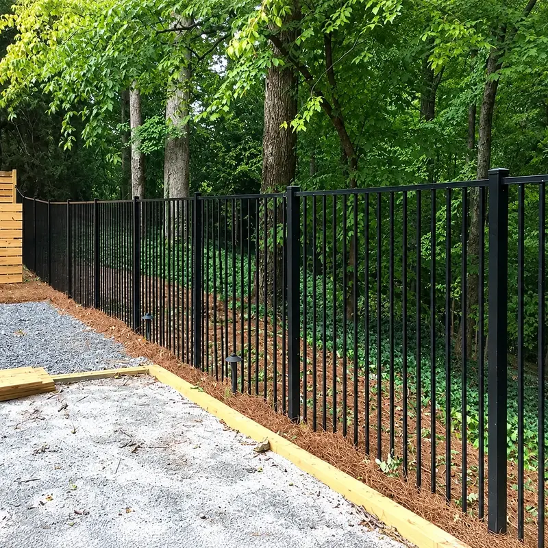 Black aluminium picket fencing following a tree-lined property boundary