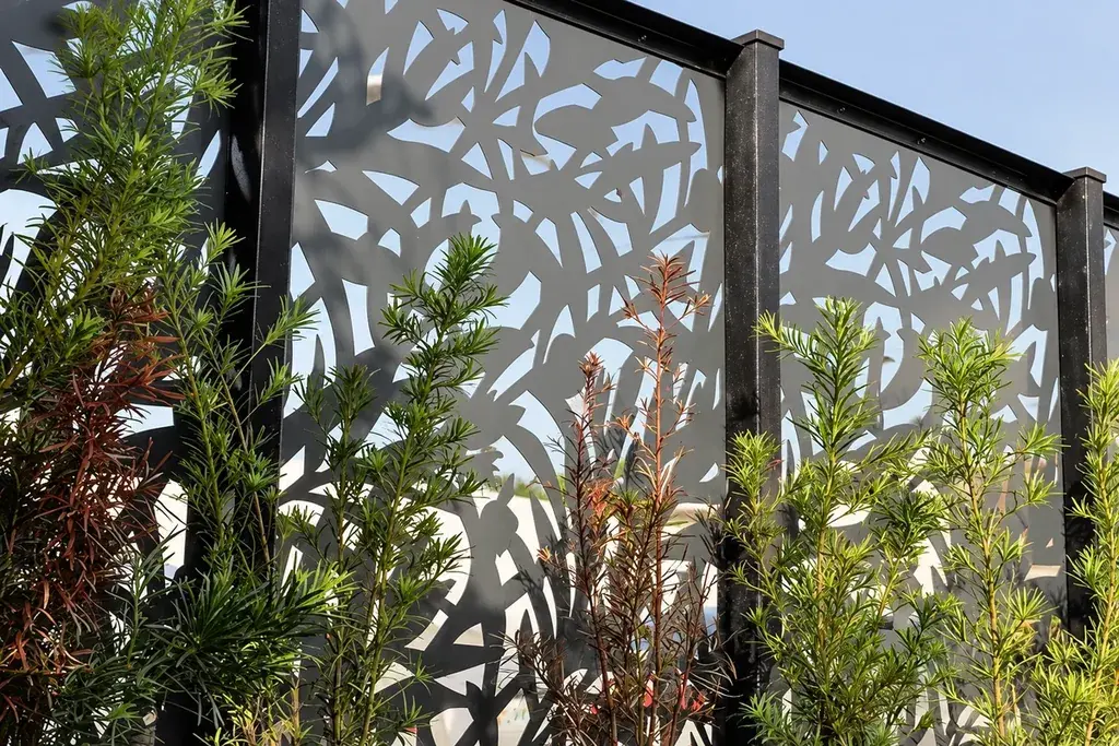 Leaf-pattern metal screens in dark frames behind garden planting