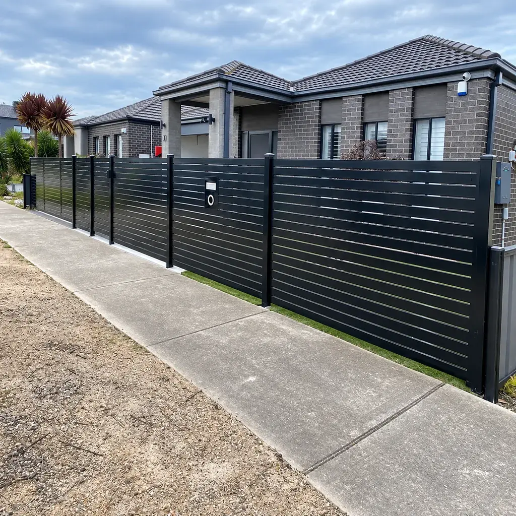 Black horizontal aluminium slat fence along a paved street edge