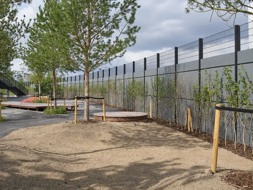 Welded mesh fence above a solid boundary beside landscaped outdoor space